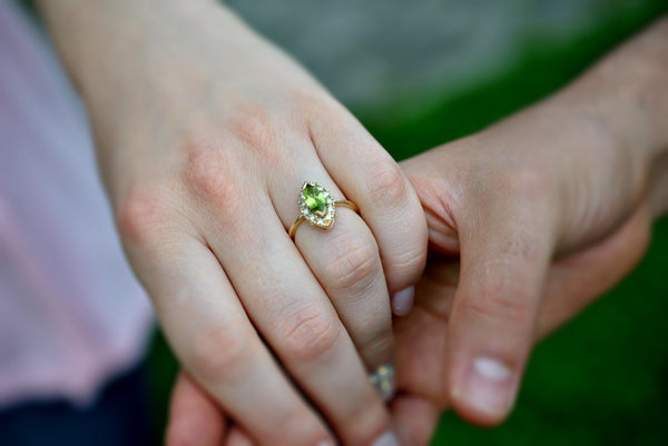 man and woman with engagement peridot and diamonds ring with a natural background
