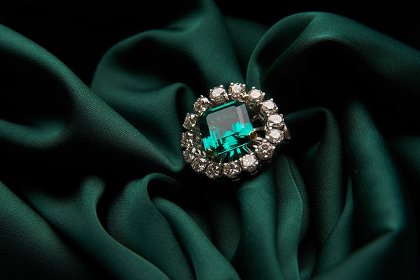 Green emerald fashion engagement diamond ring on green satin background